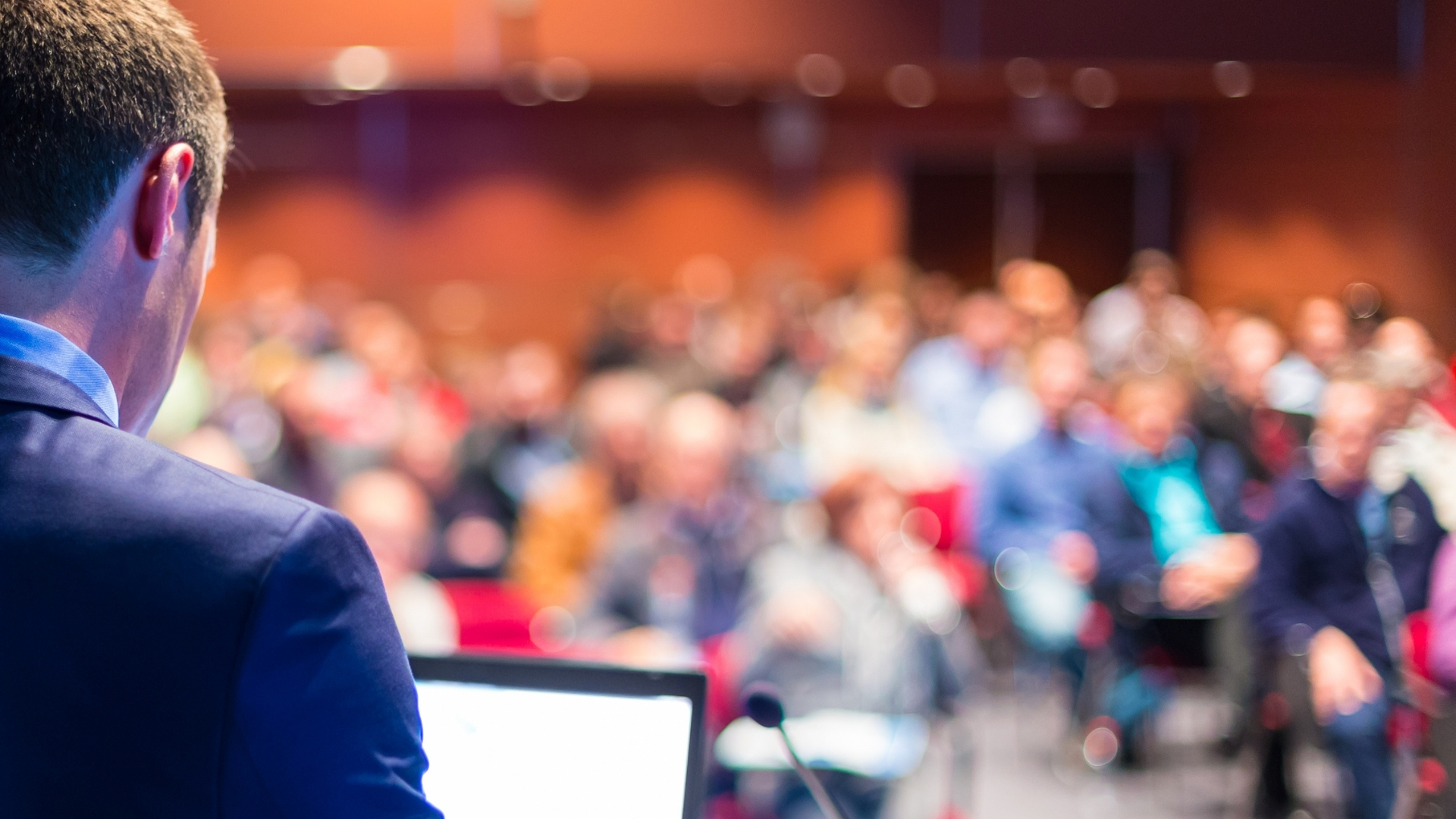 A man in a suit talking to a room full of people