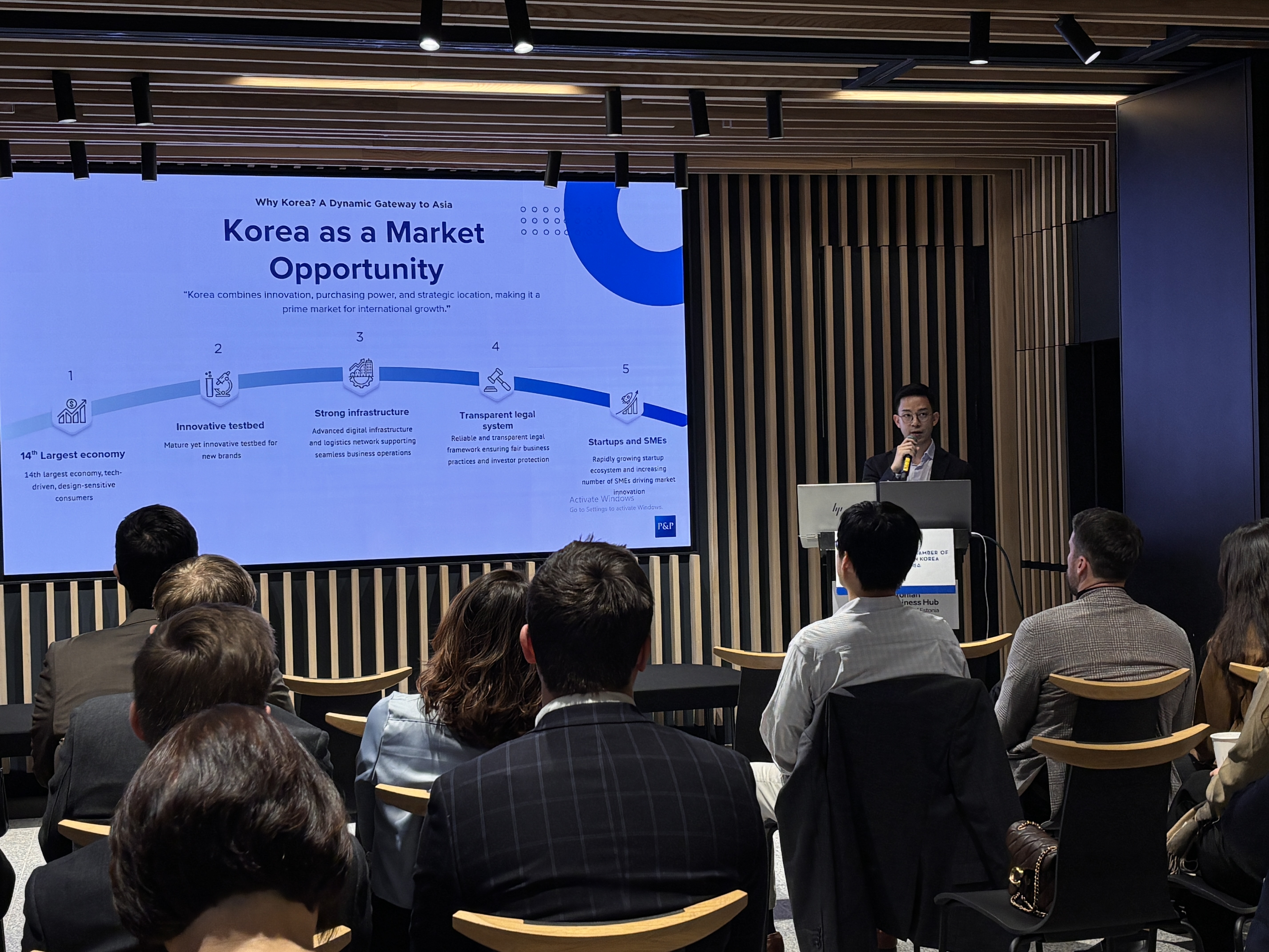 Pearson & Partners CEO presents market entry in Korea to a crowd of people with slides on the background