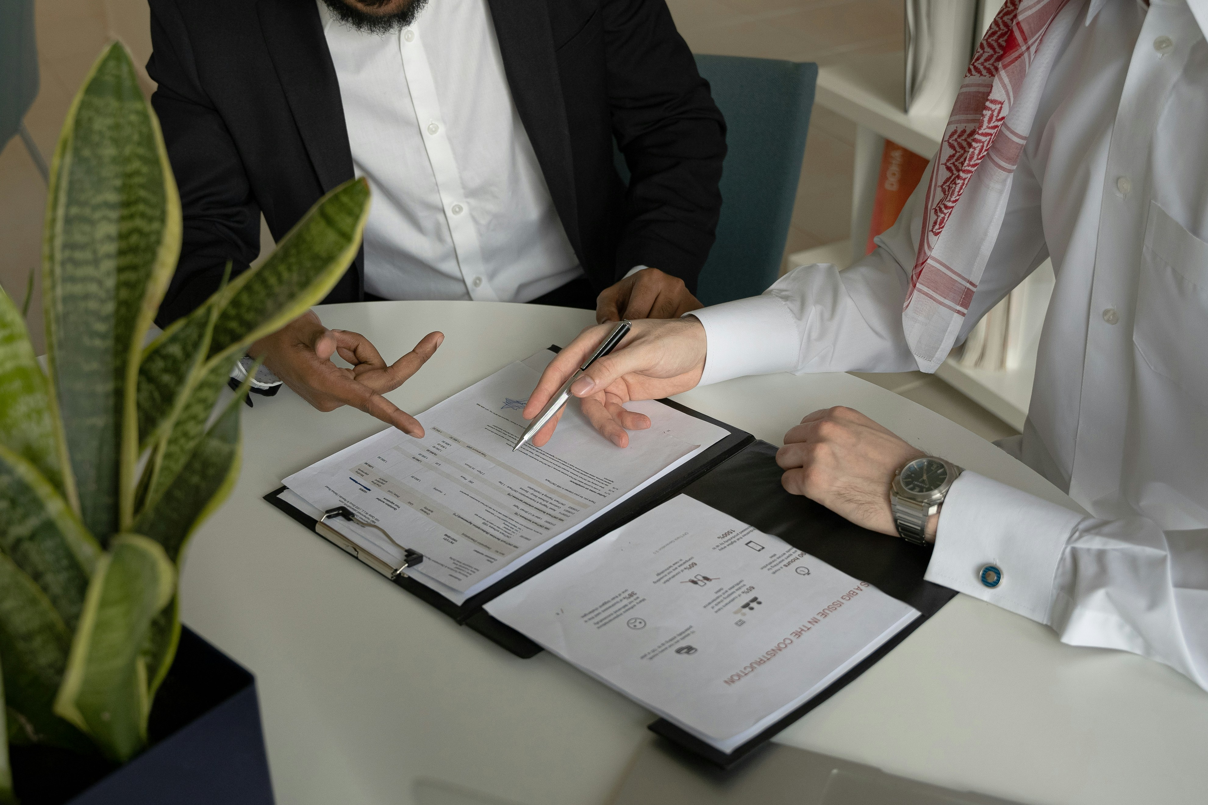 Two people sitting on a signing the papers in front of them