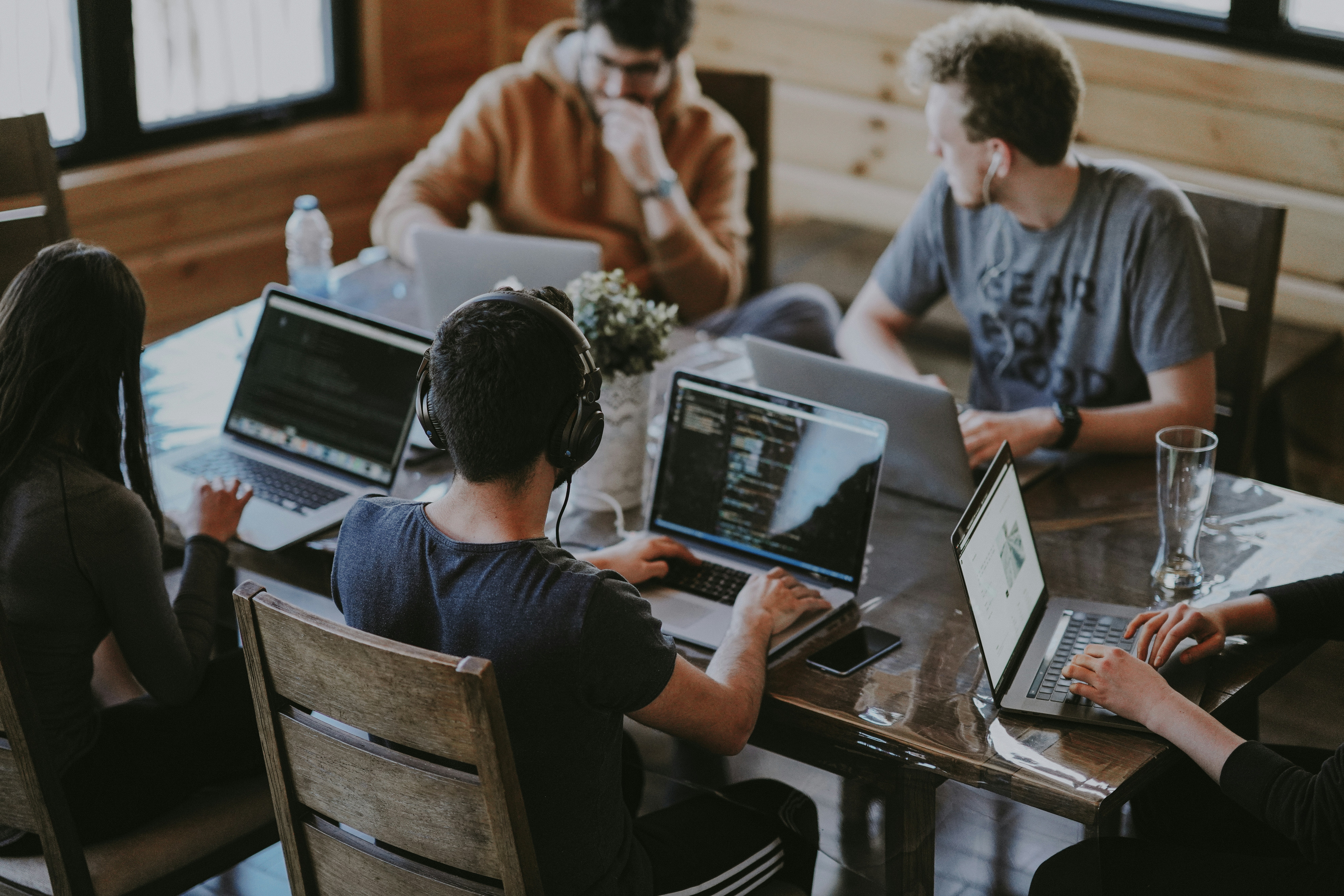 5 People working at the same table with their laptops opened, doing a work meeting