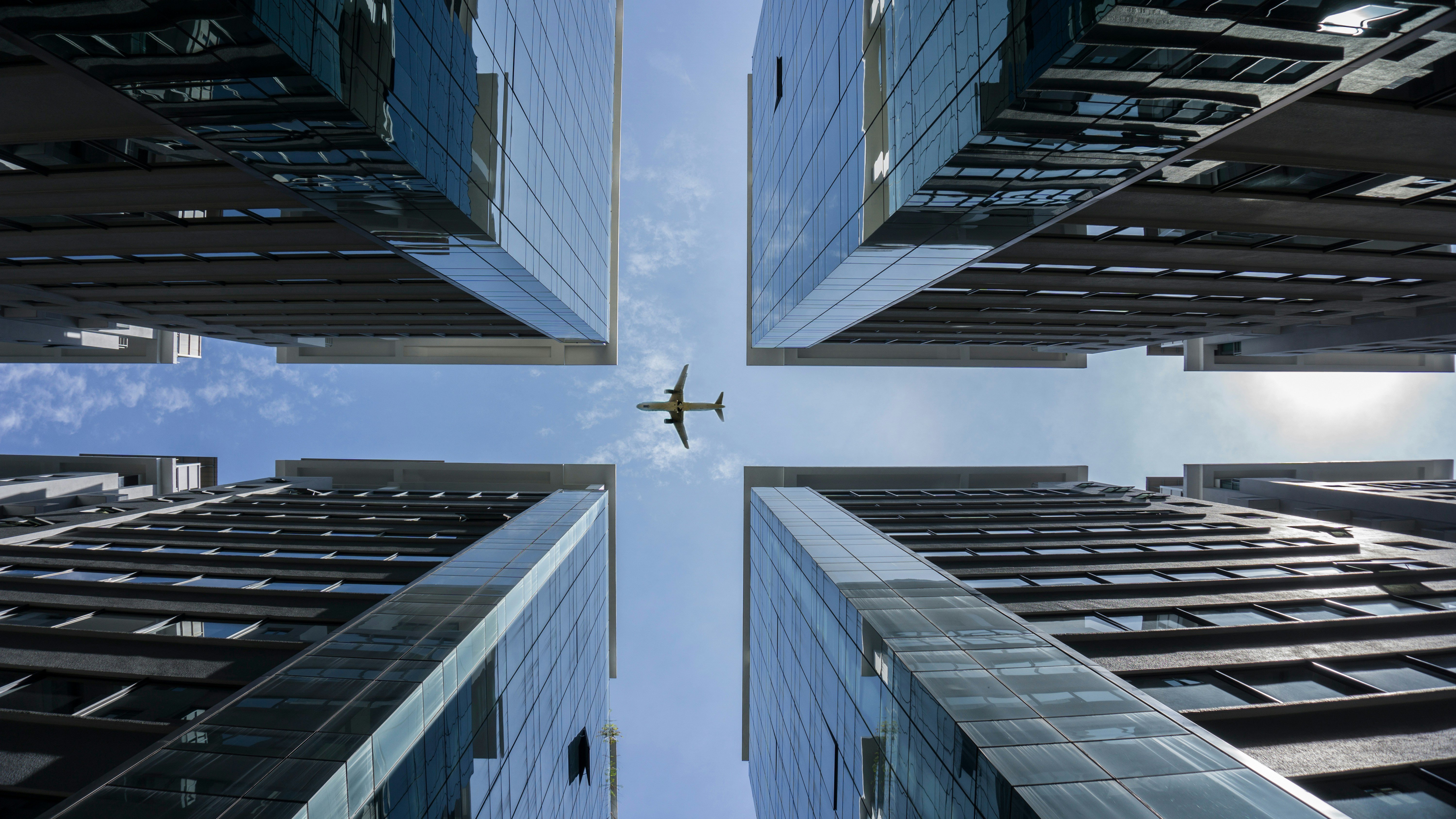 A plane passing in the space left between 4 tall buildings