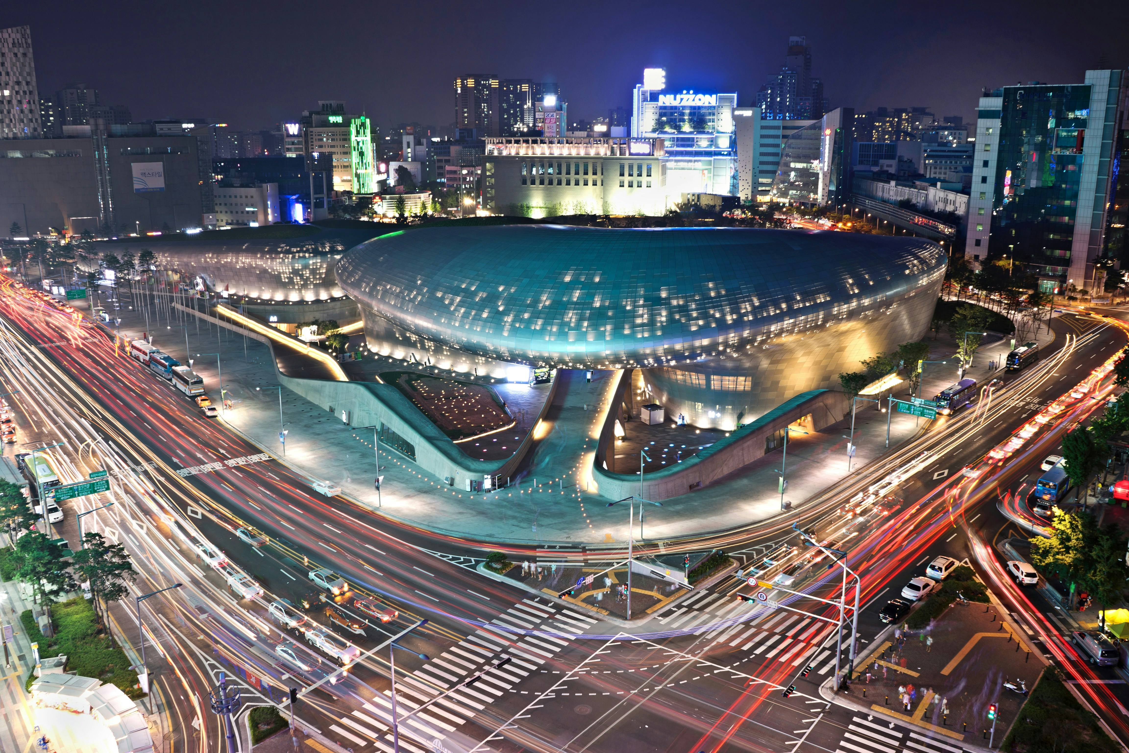 Dongdaemun Design Plaza at night, with cars passing by