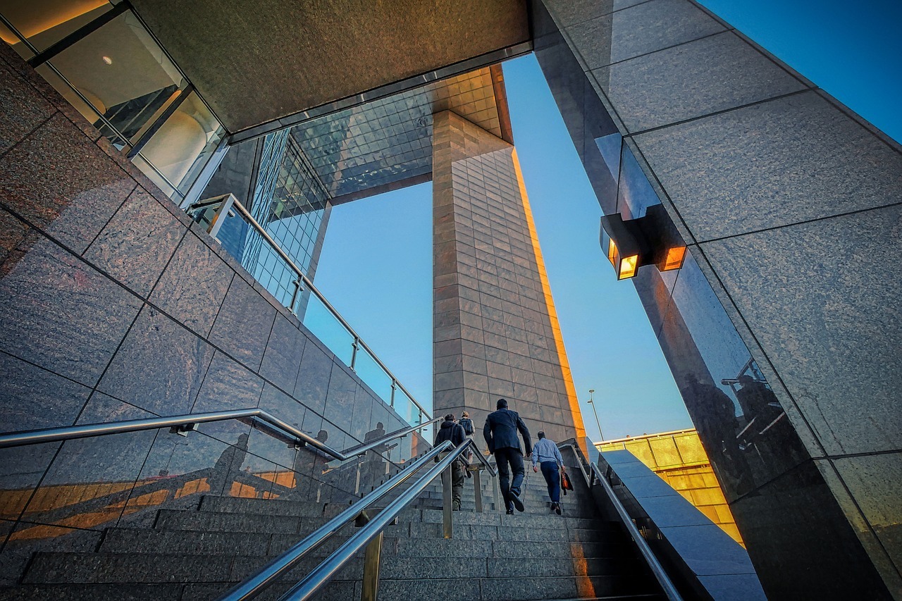 Businesses men walking up the stairs next to an office building