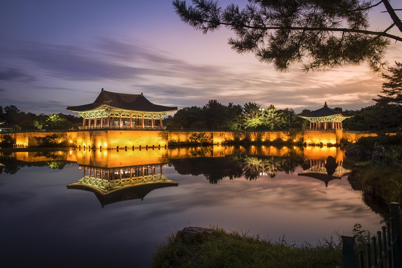 View of Donggung Palace and Wolji Pond illuminated by warm lights at sunset.